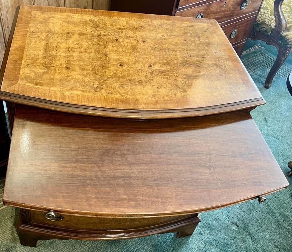 A burr walnut bow-front chest of four graduated drawers featuring brass drop handles, herringbone crossbanding, and bracket feet. View V