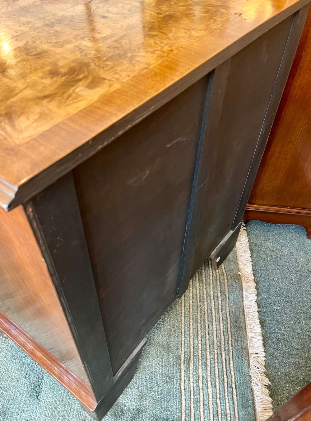 A burr walnut bow-front chest of four graduated drawers featuring brass drop handles, herringbone crossbanding, and bracket feet. View X