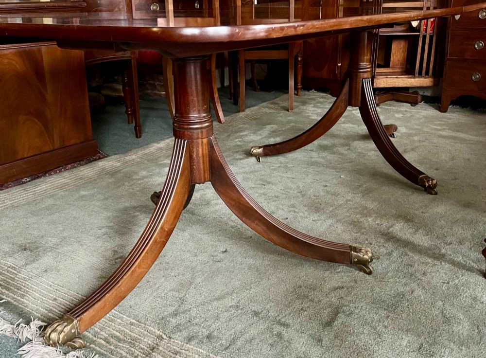 A dark brown mahogany twin pillar dining table with rounded corners and reeded splayed legs ending in brass castors. View V