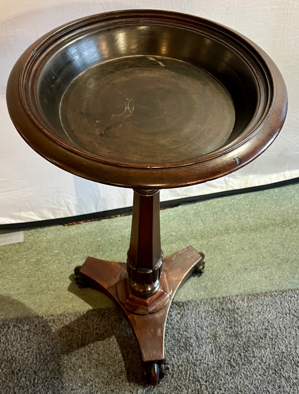 An early 19th-century rosewood wine table featuring a circular top, a tapered column, and a triform base with carved feet. View X