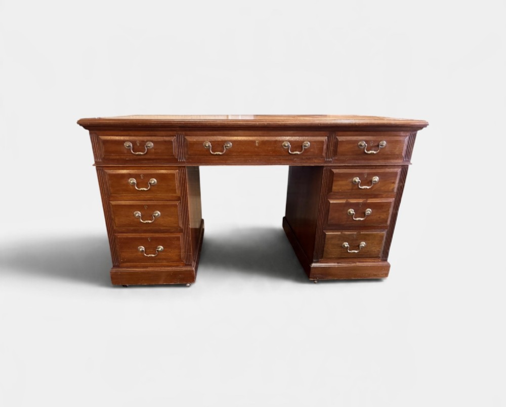 A Victorian mahogany pedestal desk featuring nine drawers with brass swan-neck handles and fluted side columns.