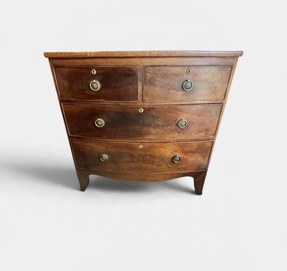 A Regency mahogany bowfront chest of drawers featuring two short over two long drawers with circular brass handles and splayed bracket feet.