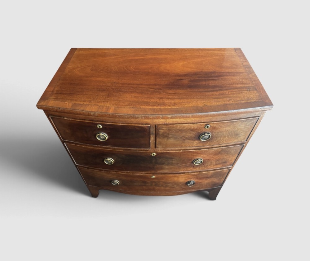 A Regency mahogany bowfront chest of drawers featuring two short over two long drawers with circular brass handles and splayed bracket feet. View III