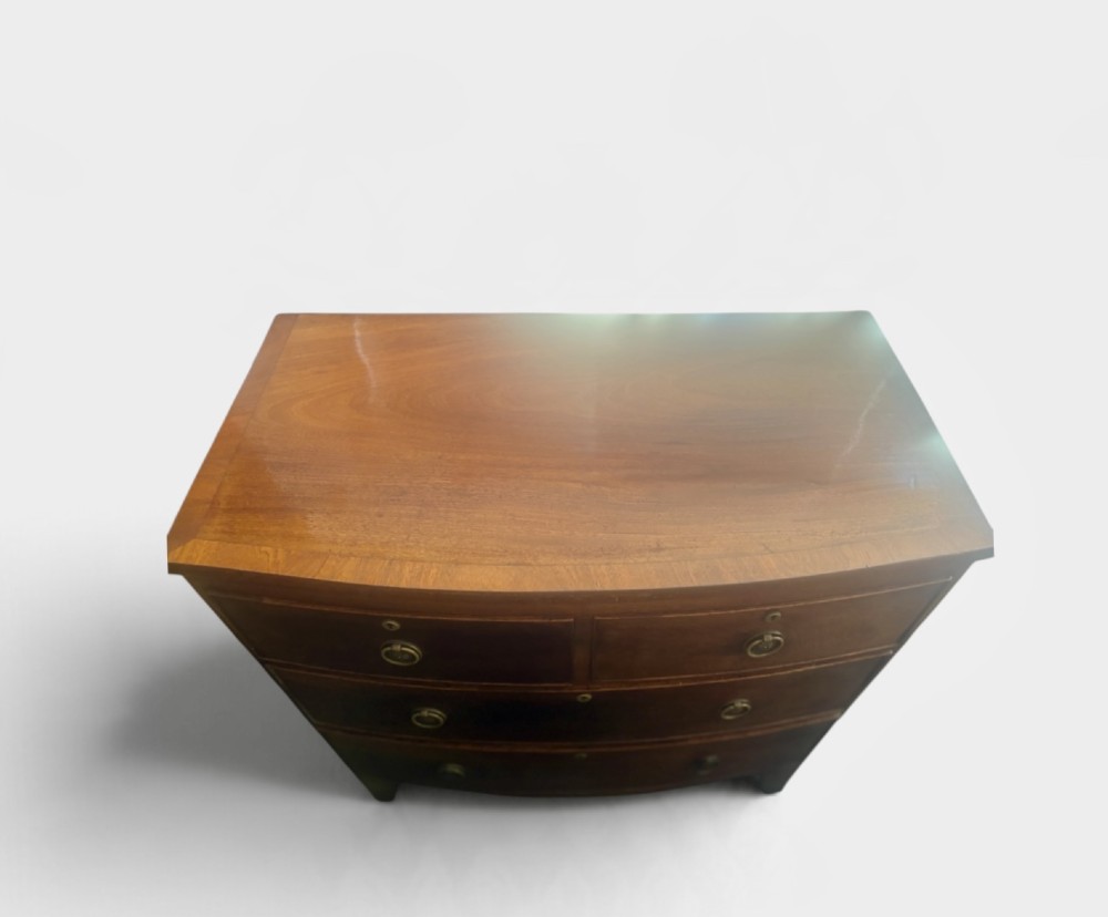 A Regency mahogany bowfront chest of drawers featuring two short over two long drawers with circular brass handles and splayed bracket feet. View IV