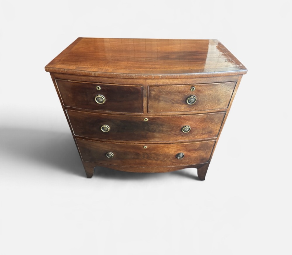 A Regency mahogany bowfront chest of drawers featuring two short over two long drawers with circular brass handles and splayed bracket feet. View V