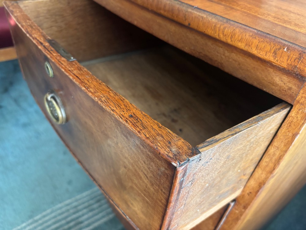 A Regency mahogany bowfront chest of drawers featuring two short over two long drawers with circular brass handles and splayed bracket feet. View VI