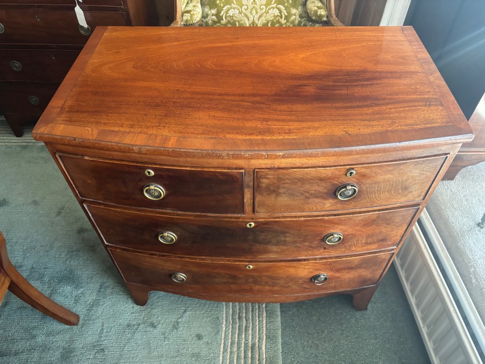 A Regency mahogany bowfront chest of drawers featuring two short over two long drawers with circular brass handles and splayed bracket feet. View VII