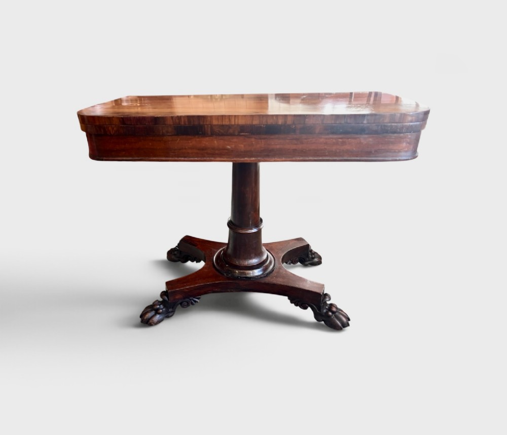 A William IV rosewood fold-over card table featuring a cylindrical central pedestal resting on a concave four-point base with carved lion claw feet. View II