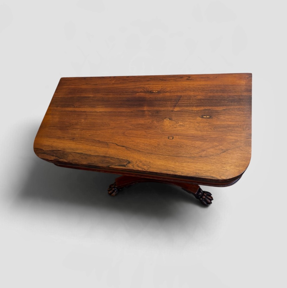 A William IV rosewood fold-over card table featuring a cylindrical central pedestal resting on a concave four-point base with carved lion claw feet. View III
