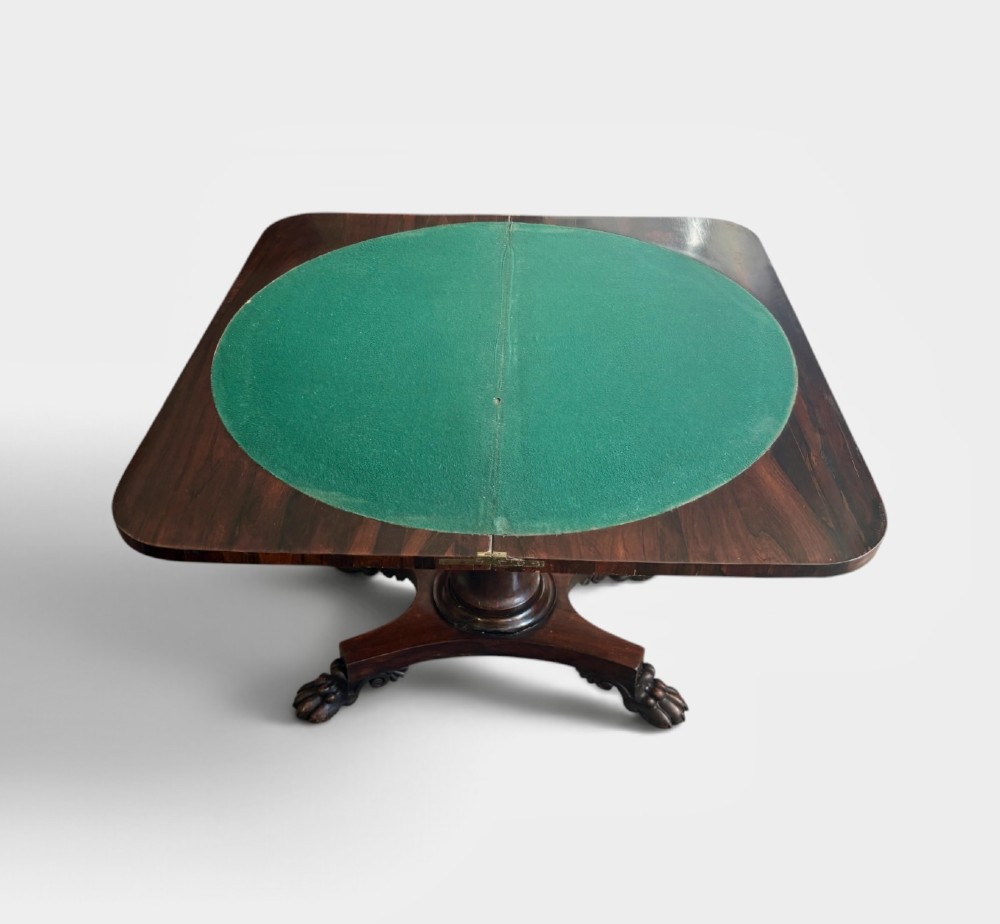 A William IV rosewood fold-over card table featuring a cylindrical central pedestal resting on a concave four-point base with carved lion claw feet. View IV