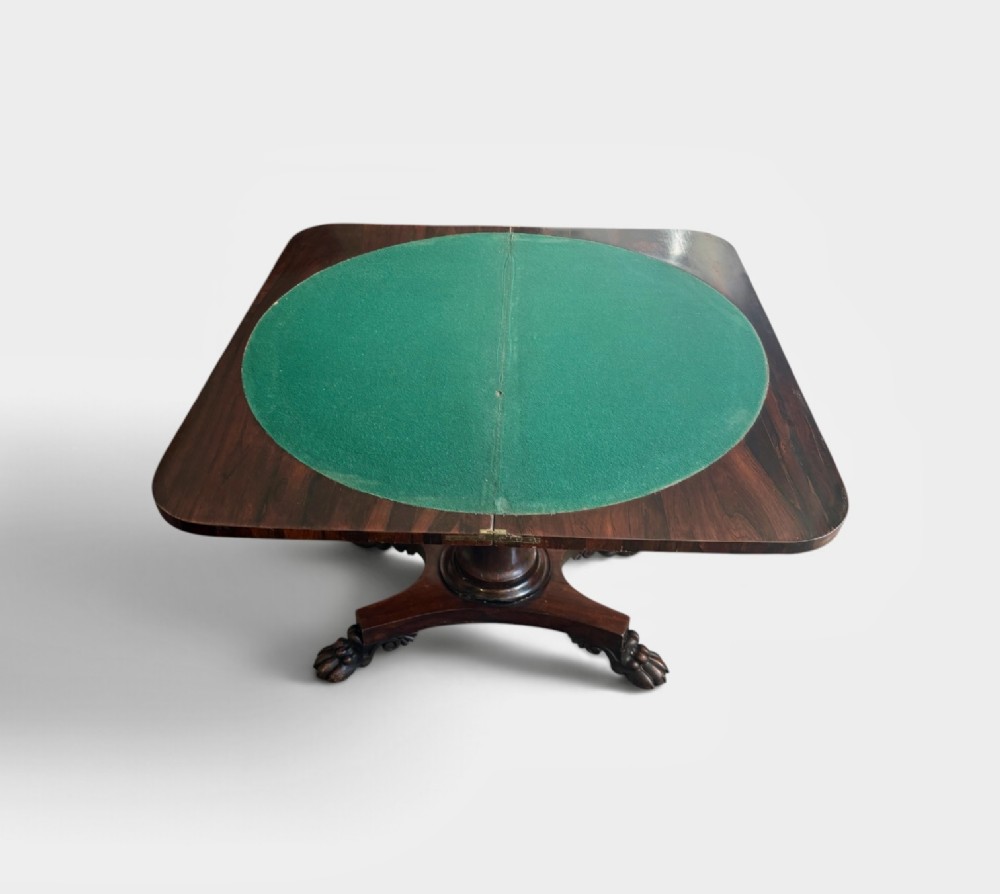 A William IV rosewood fold-over card table featuring a cylindrical central pedestal resting on a concave four-point base with carved lion claw feet. View V