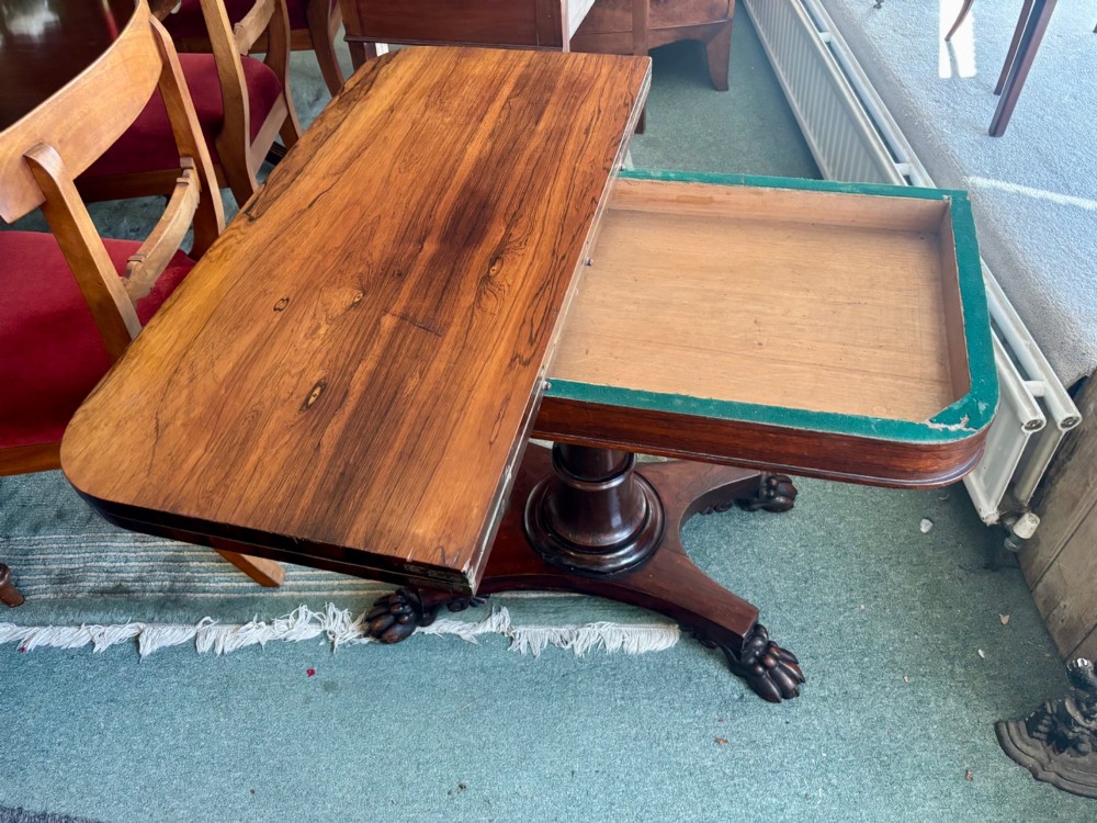 A William IV rosewood fold-over card table featuring a cylindrical central pedestal resting on a concave four-point base with carved lion claw feet. View VI