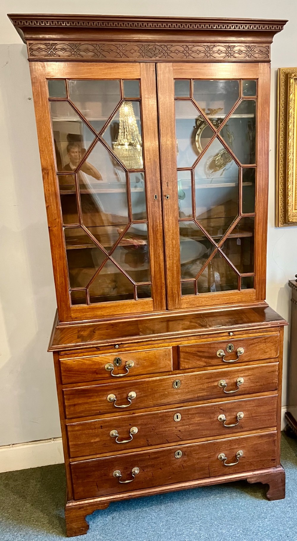 A George III mahogany library bookcase featuring astragal glazed upper doors above a chest of four drawers with brass swan-neck handles.