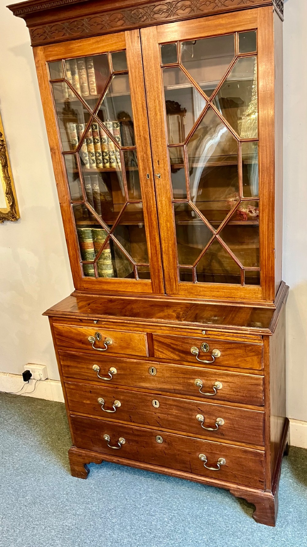 A George III mahogany library bookcase featuring astragal glazed upper doors above a chest of four drawers with brass swan-neck handles. View III
