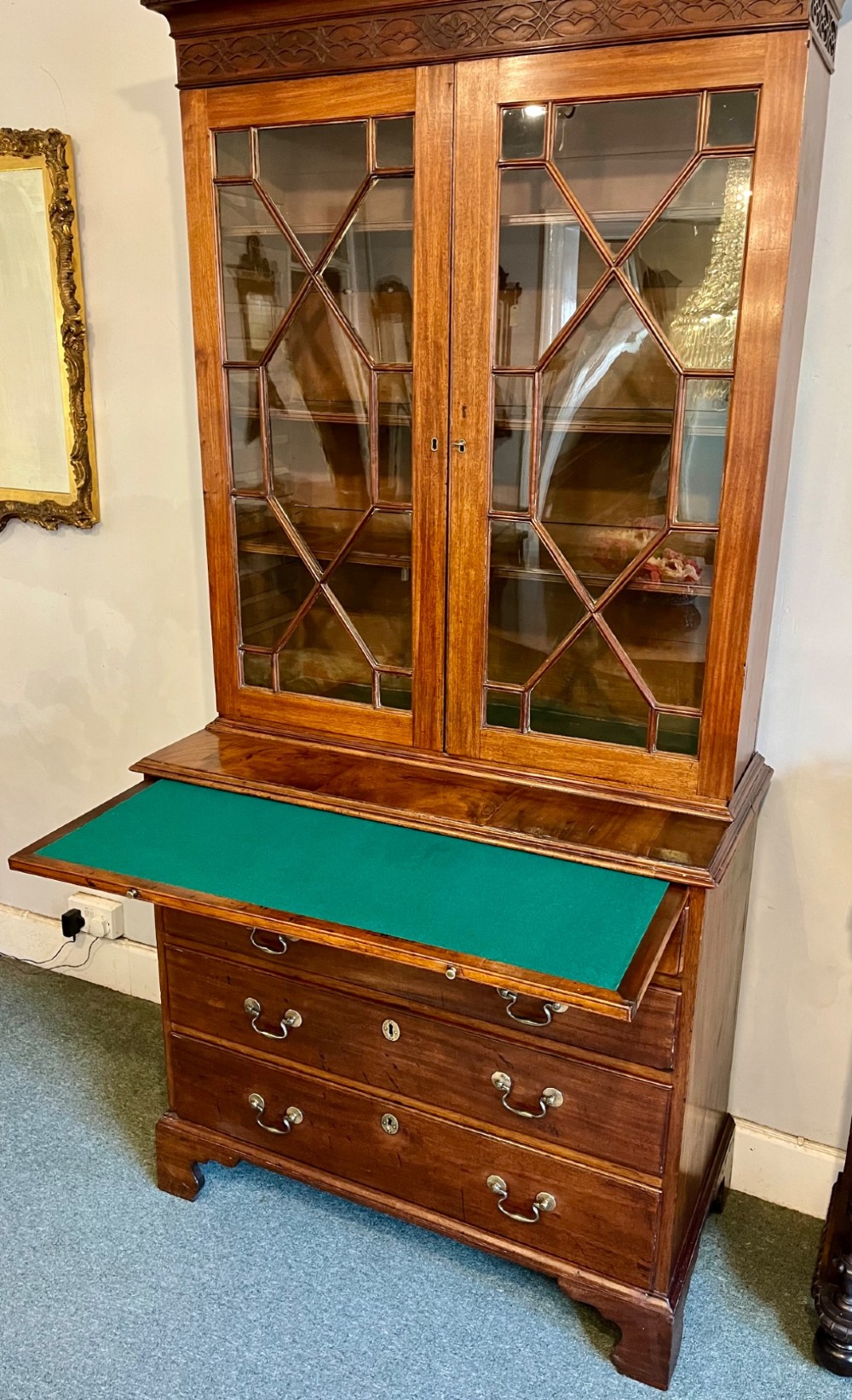 A George III mahogany library bookcase featuring astragal glazed upper doors above a chest of four drawers with brass swan-neck handles. View VI