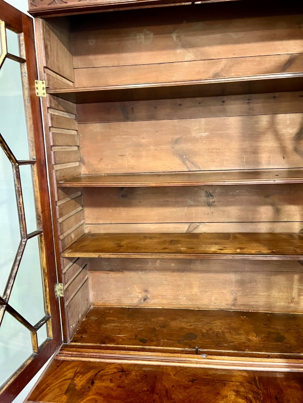 A George III mahogany library bookcase featuring astragal glazed upper doors above a chest of four drawers with brass swan-neck handles. View VII