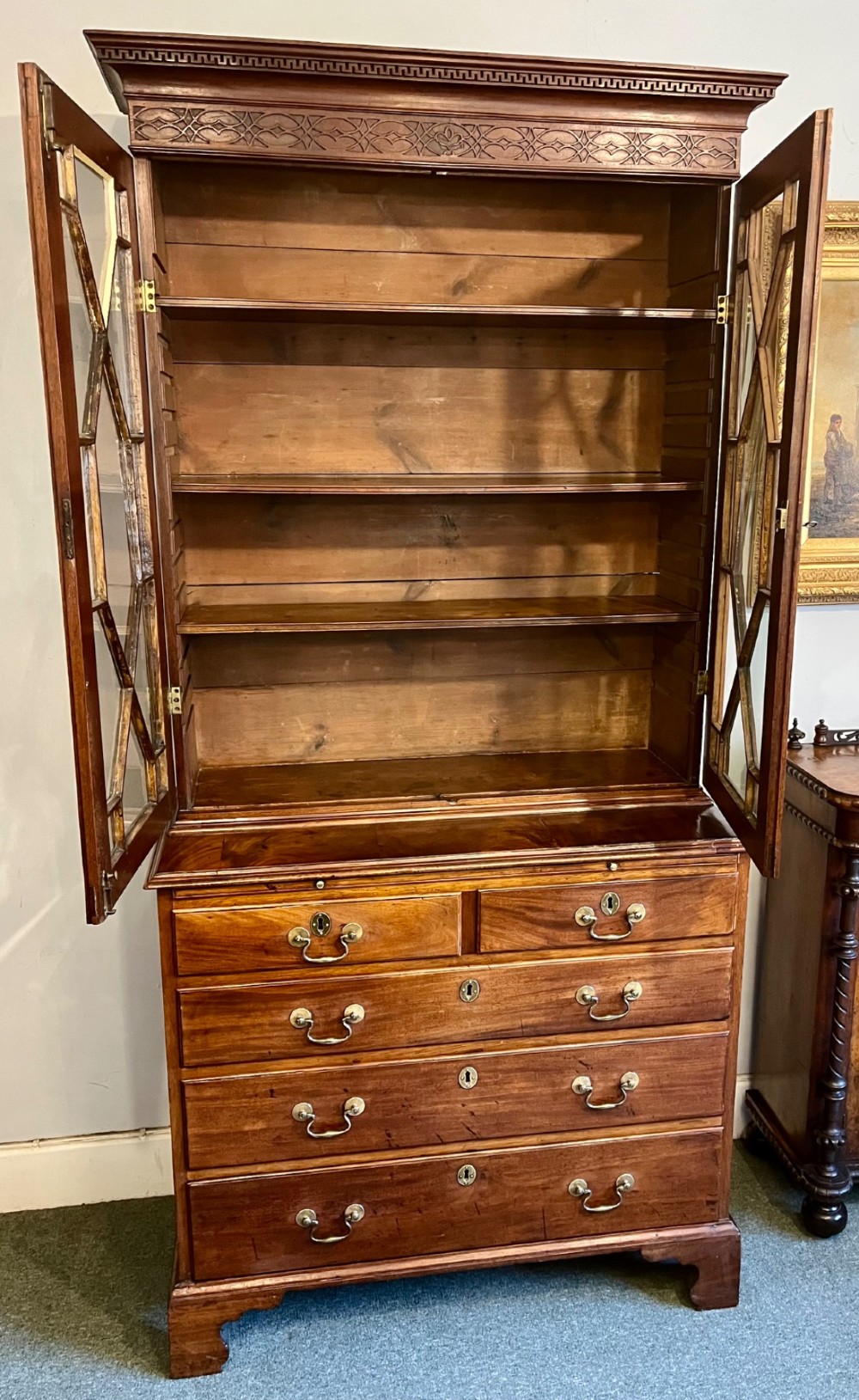 A George III mahogany library bookcase featuring astragal glazed upper doors above a chest of four drawers with brass swan-neck handles. View VIII