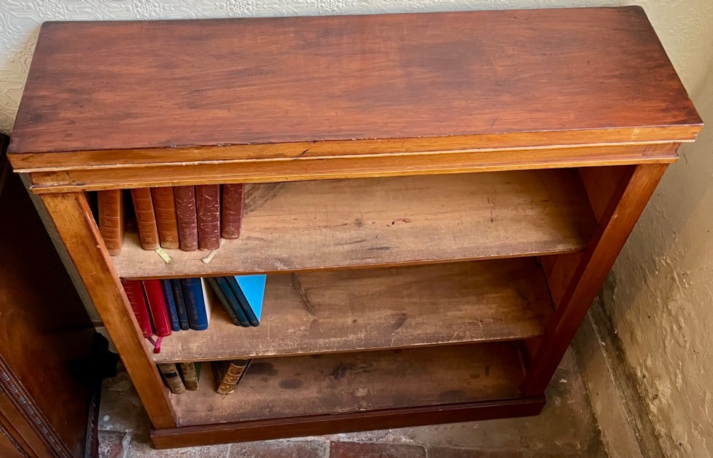 A low Victorian open mahogany bookcase featuring three wide shelves, exposed vertical backboards, a top edge, and a plinth base. View V