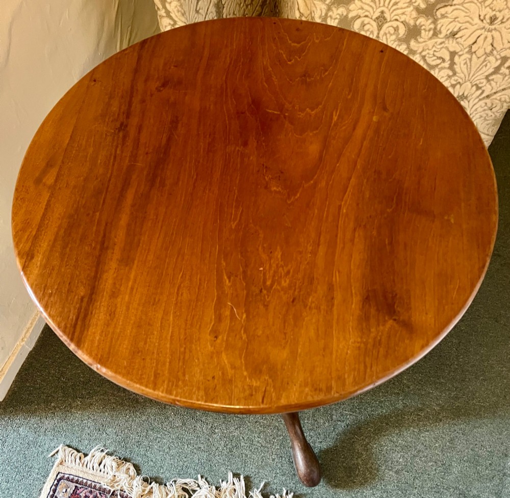 A nineteenth-century mahogany tripod table featuring a circular top resting on a turned and carved central pedestal with three cabriole legs. View III