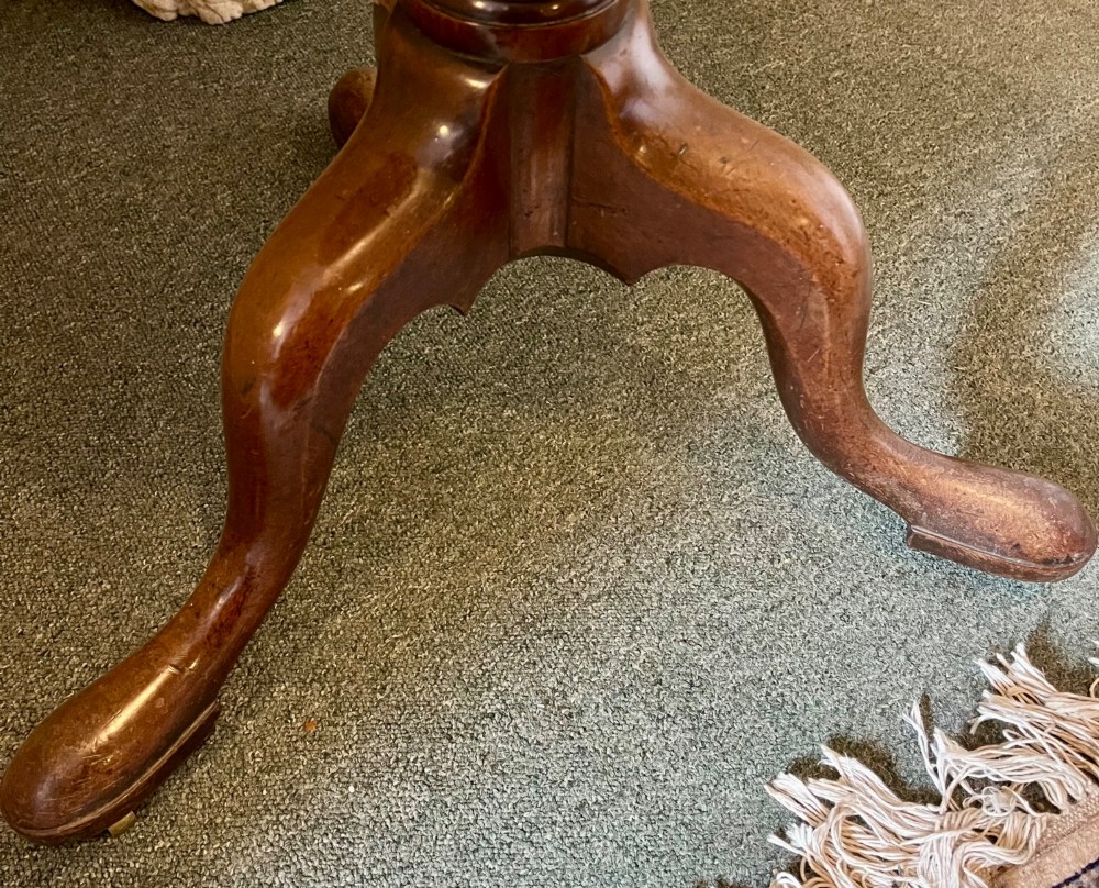 A nineteenth-century mahogany tripod table featuring a circular top resting on a turned and carved central pedestal with three cabriole legs. View V