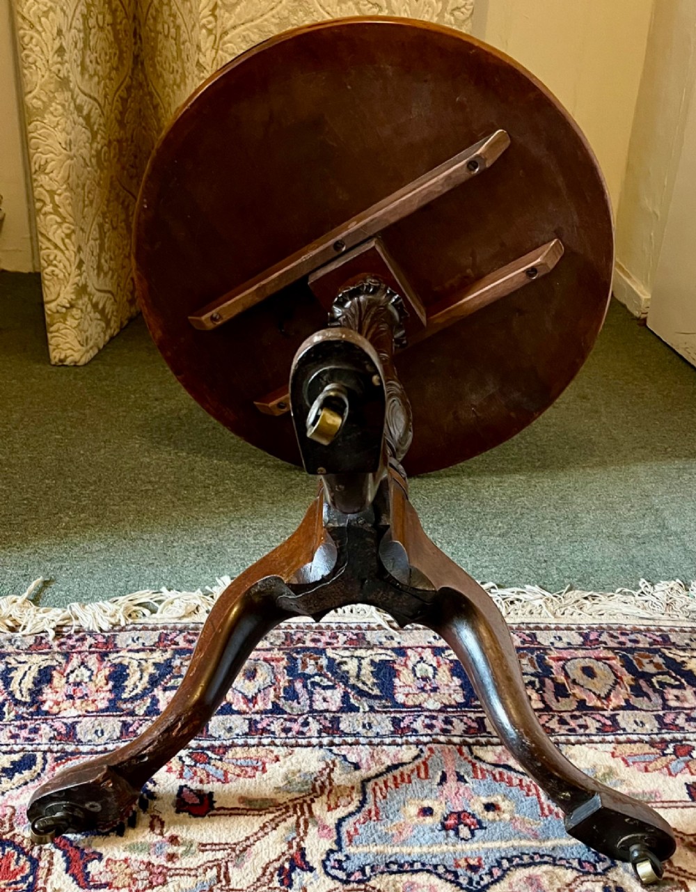 A nineteenth-century mahogany tripod table featuring a circular top resting on a turned and carved central pedestal with three cabriole legs. View VI