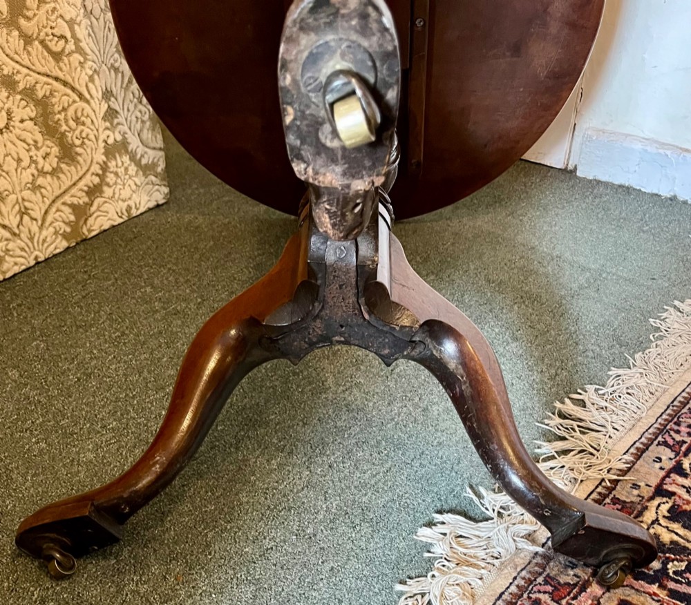 A nineteenth-century mahogany tripod table featuring a circular top resting on a turned and carved central pedestal with three cabriole legs. View VII