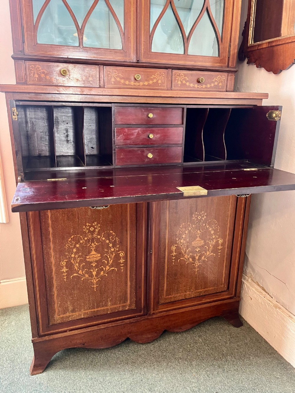 An Edwardian mahogany secretaire bookcase featuring satinwood marquetry inlays, a swan-neck pediment, glazed upper doors, and a pull-out desk drawer above lower cupboards. View XI
