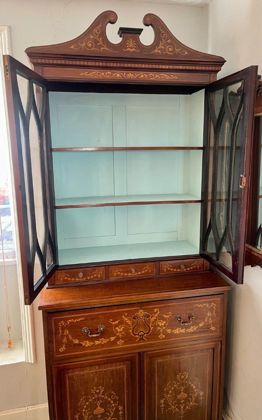 An Edwardian mahogany secretaire bookcase featuring satinwood marquetry inlays, a swan-neck pediment, glazed upper doors, and a pull-out desk drawer above lower cupboards. View XIII