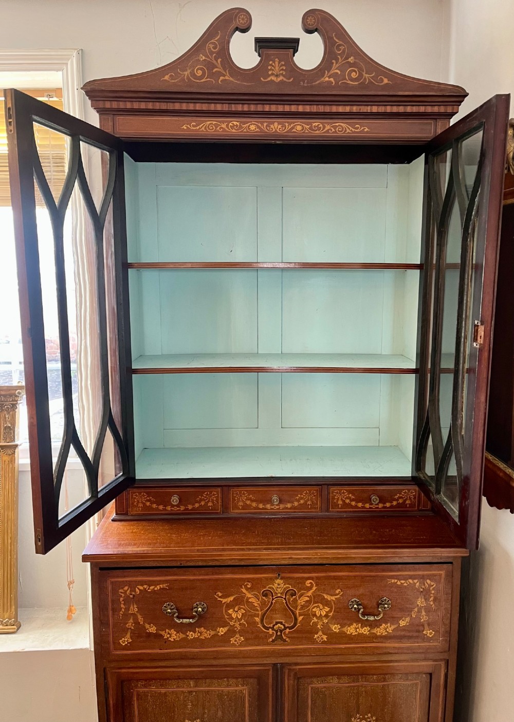 An Edwardian mahogany secretaire bookcase featuring satinwood marquetry inlays, a swan-neck pediment, glazed upper doors, and a pull-out desk drawer above lower cupboards. View XIV