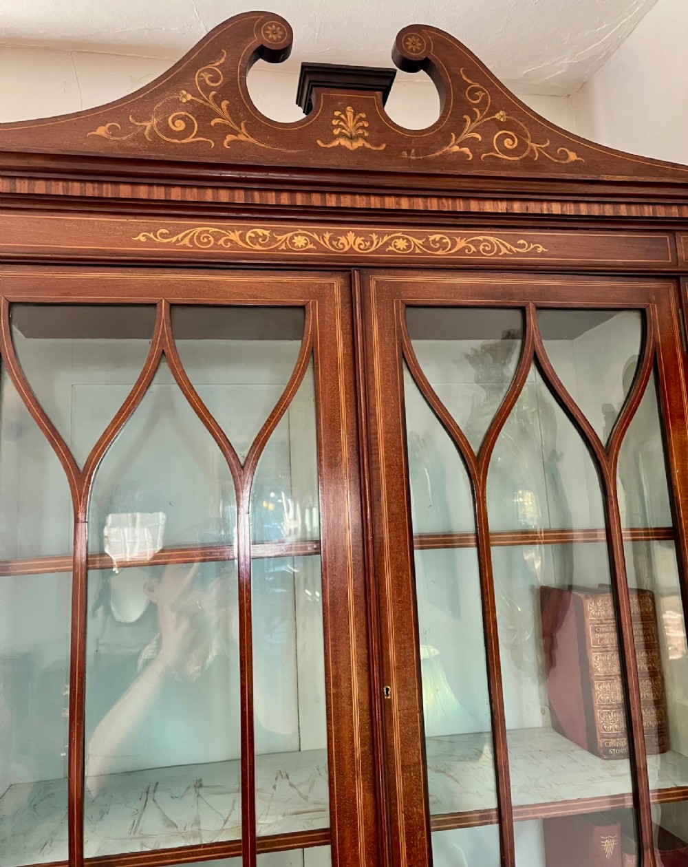 An Edwardian mahogany secretaire bookcase featuring satinwood marquetry inlays, a swan-neck pediment, glazed upper doors, and a pull-out desk drawer above lower cupboards. View XV