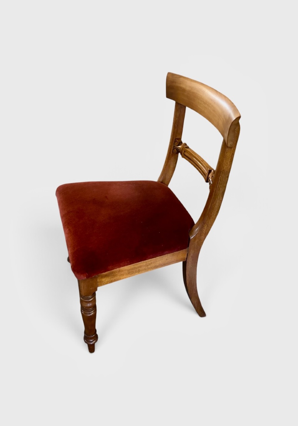 A set of six early Victorian mahogany dining chairs lined up, featuring turned front legs, curved top rails, and red velvet upholstered seats. View IV