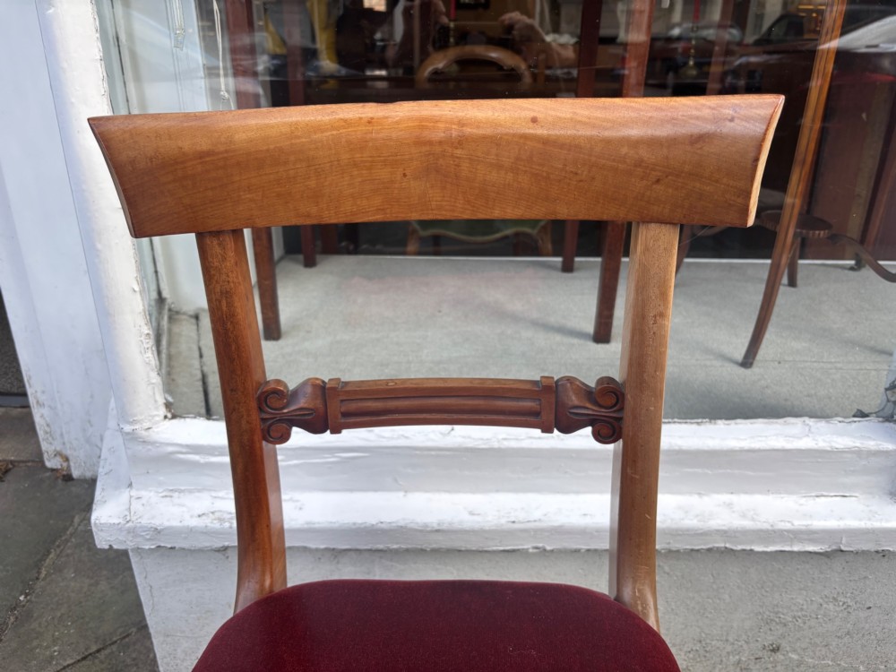 A set of six early Victorian mahogany dining chairs lined up, featuring turned front legs, curved top rails, and red velvet upholstered seats. View VI