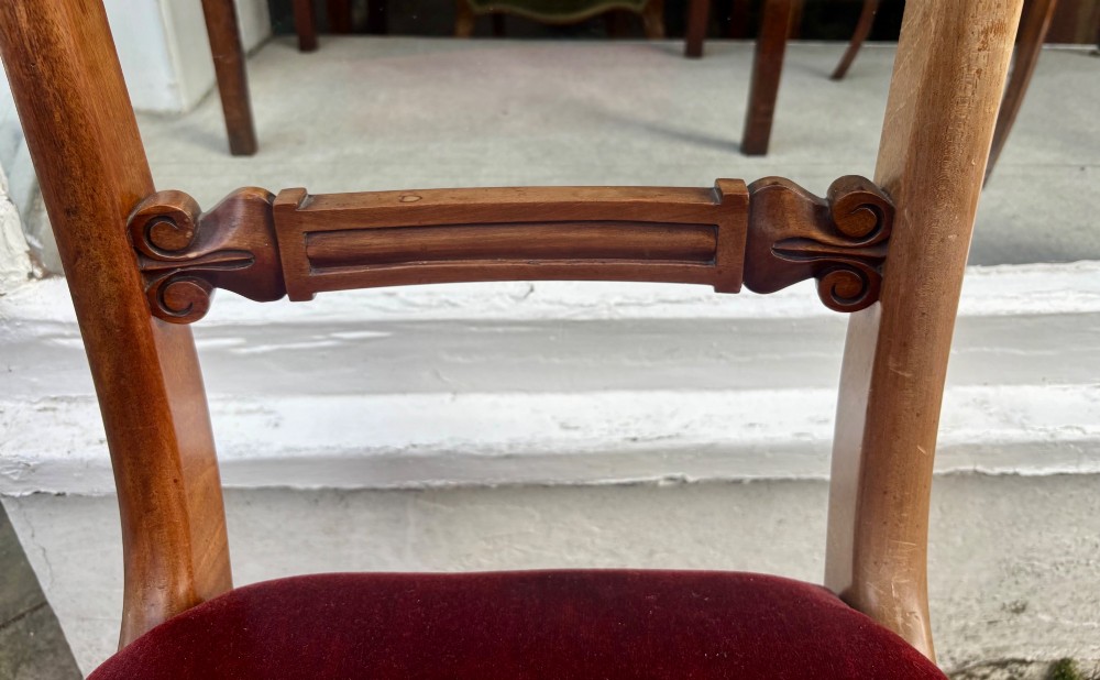 A set of six early Victorian mahogany dining chairs lined up, featuring turned front legs, curved top rails, and red velvet upholstered seats. View VII