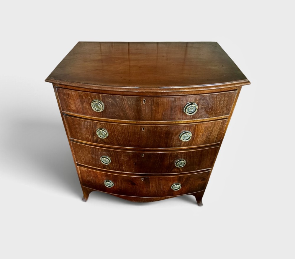 A small Edwardian mahogany bow front chest of drawers featuring four graduated drawers with brass ring drop handles and bracket feet. View II