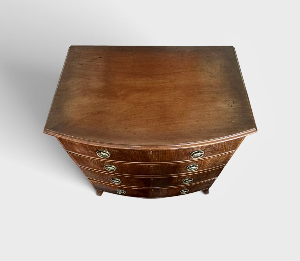 A small Edwardian mahogany bow front chest of drawers featuring four graduated drawers with brass ring drop handles and bracket feet. View III