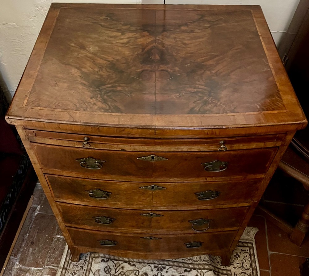 An Edwardian bow-fronted chest of drawers crafted from figured walnut with brass handles and cross-banded detailing. View II