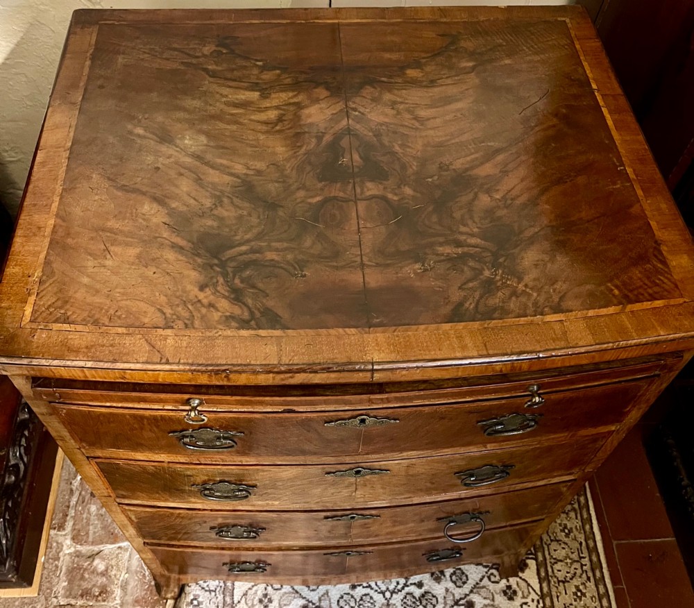 An Edwardian bow-fronted chest of drawers crafted from figured walnut with brass handles and cross-banded detailing. View III