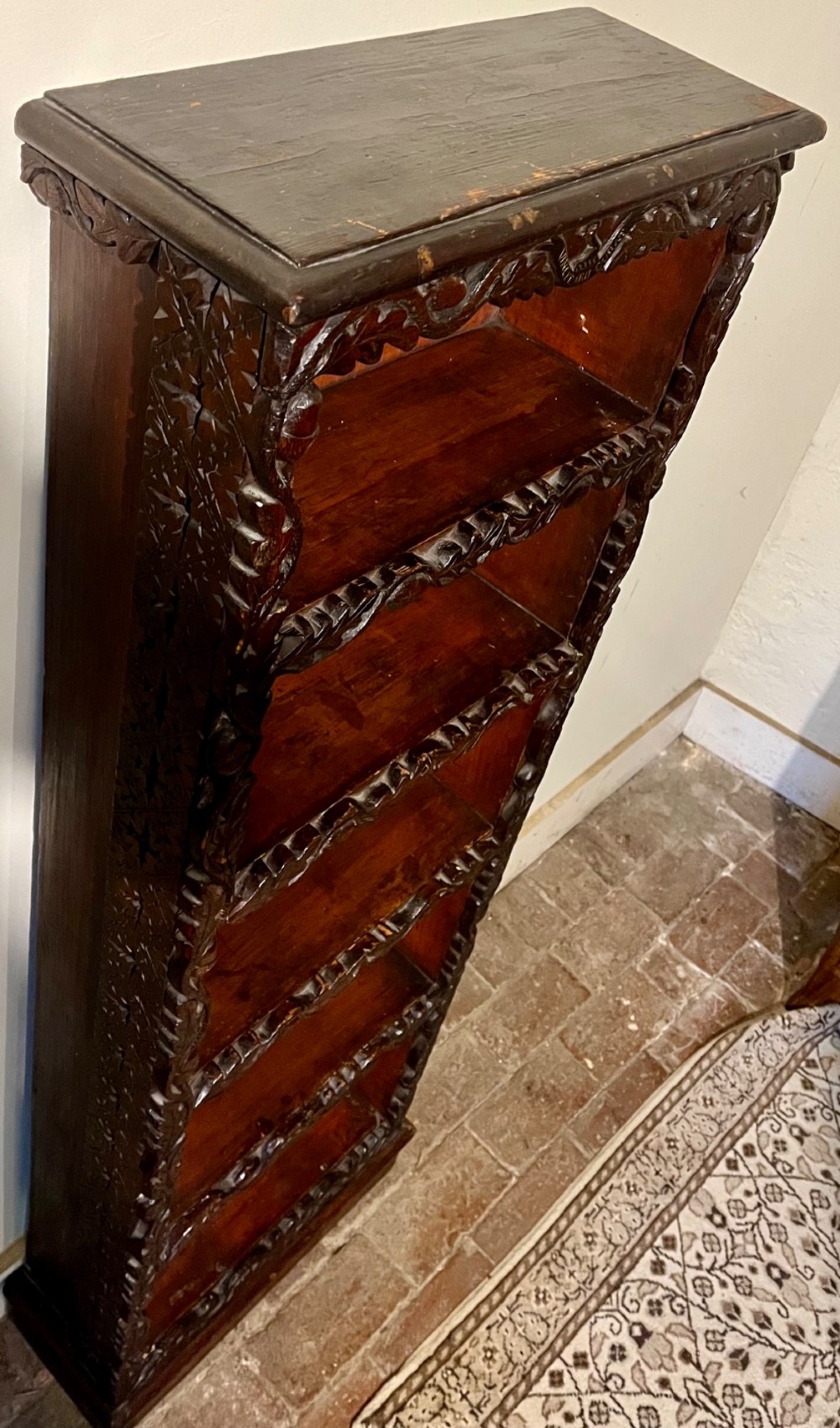 A tall, narrow Victorian open bookcase made of dark carved oak and pine with five shelves decorated with leaf borders. View II