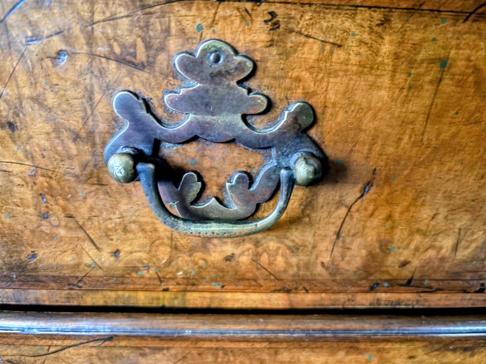 An antique burr walnut bachelors chest featuring a hinged fold-over top, four graduated drawers with brass handles, and bracket feet. View VIII