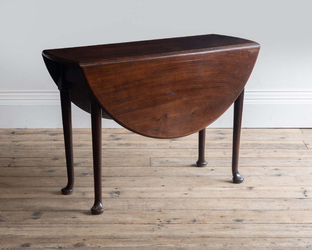A Georgian dark mahogany oval supper table featuring two drop leaves supported by slender legs with pad feet. View II