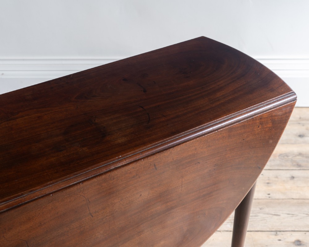 A Georgian dark mahogany oval supper table featuring two drop leaves supported by slender legs with pad feet. View III