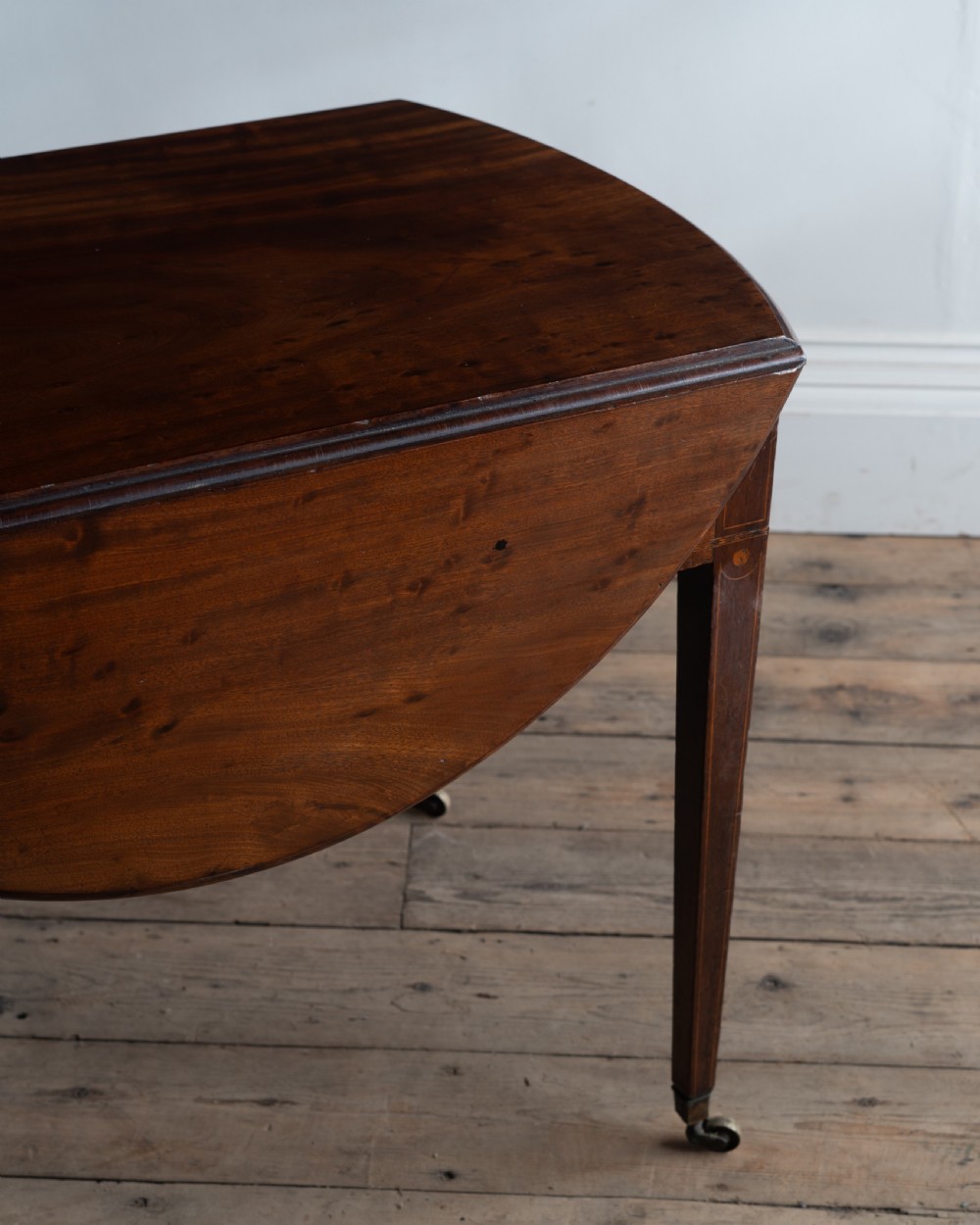 A George III mahogany Pembroke table with rounded drop leaves, a single drawer with brass pull handle, and tapered legs ending in brass castors. View III