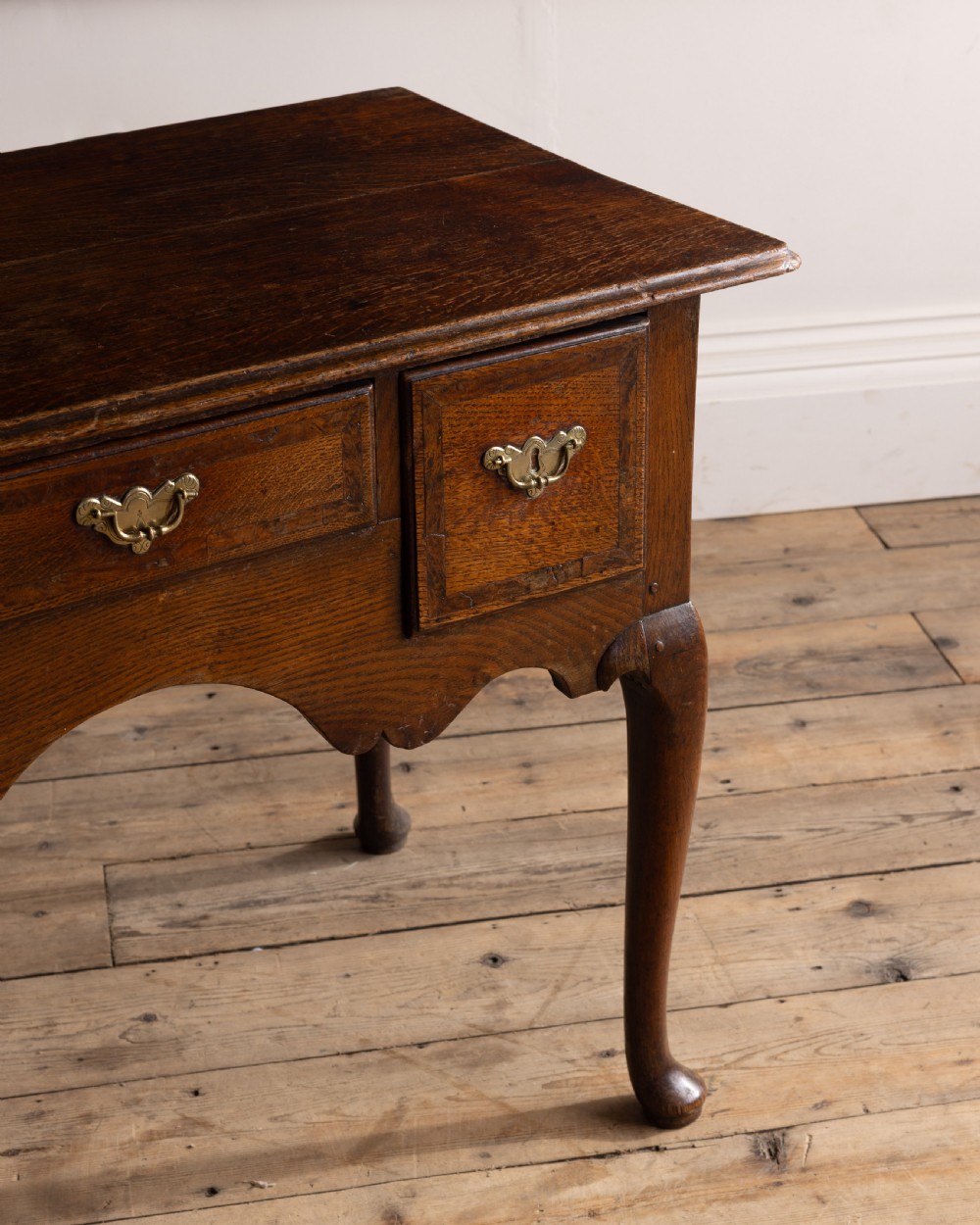 A Georgian oak low boy featuring three drawers with brass handles, a shaped apron, and cabriole legs resting on pad feet. View II
