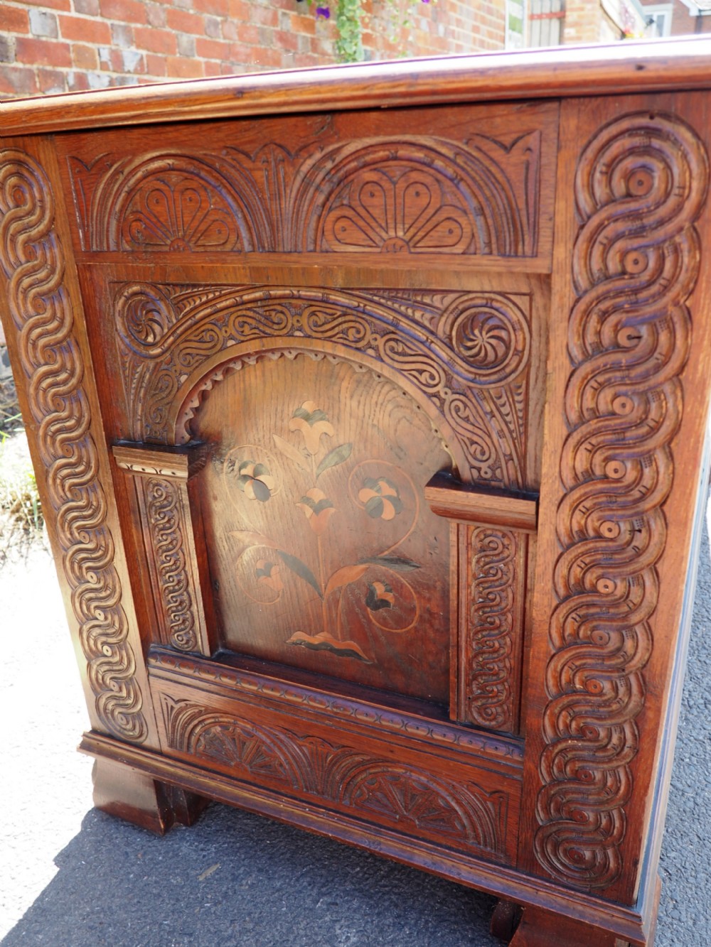 A rectangular carved oak coffer with three arcaded front panels featuring floral inlay and a flat panelled top. View V