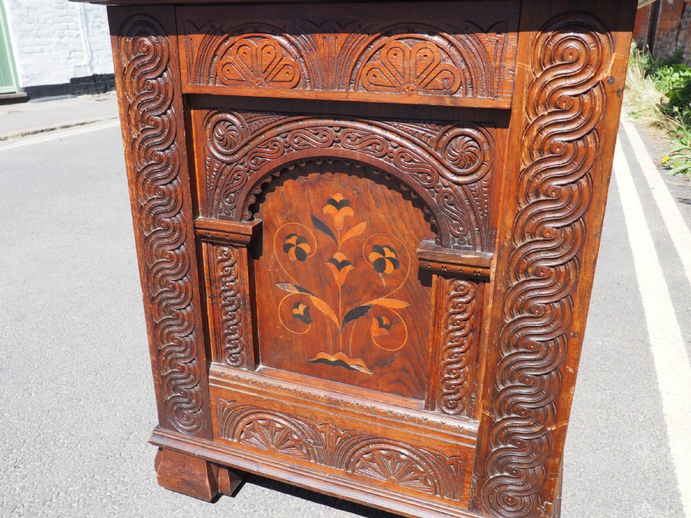 A rectangular carved oak coffer with three arcaded front panels featuring floral inlay and a flat panelled top. View VI