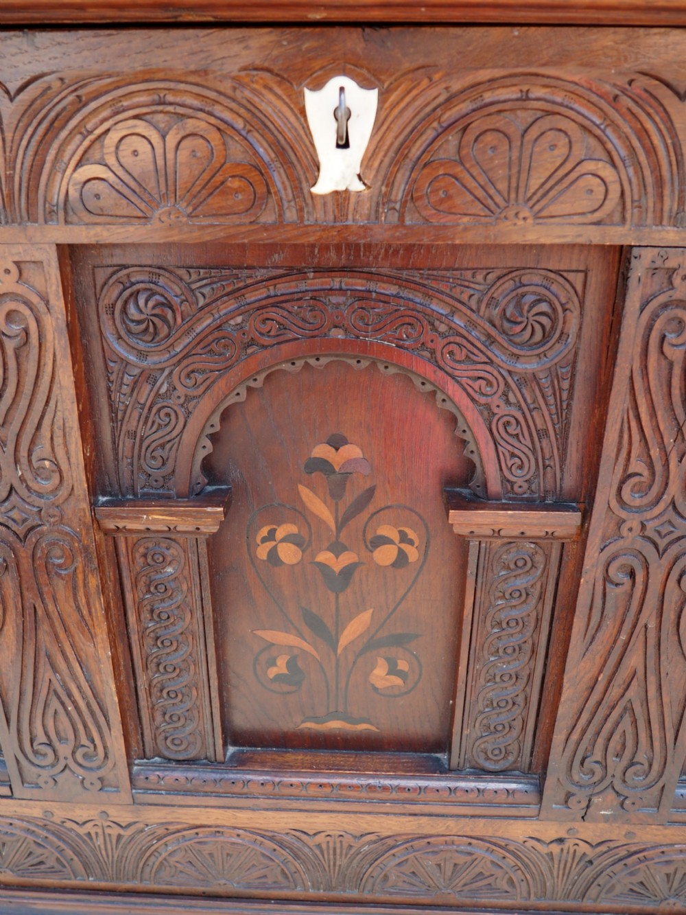 A rectangular carved oak coffer with three arcaded front panels featuring floral inlay and a flat panelled top. View XIV