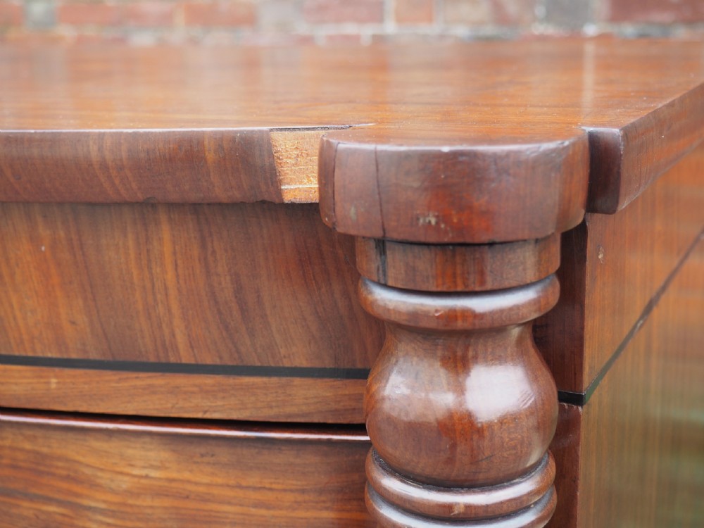 A Regency period mahogany bowfront chest of drawers featuring three full-width drawers, spiral-turned side columns, and circular brass handles. View II