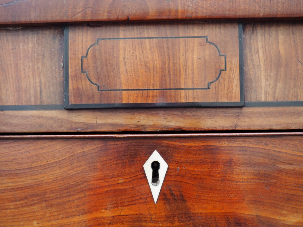 A Regency period mahogany bowfront chest of drawers featuring three full-width drawers, spiral-turned side columns, and circular brass handles. View V