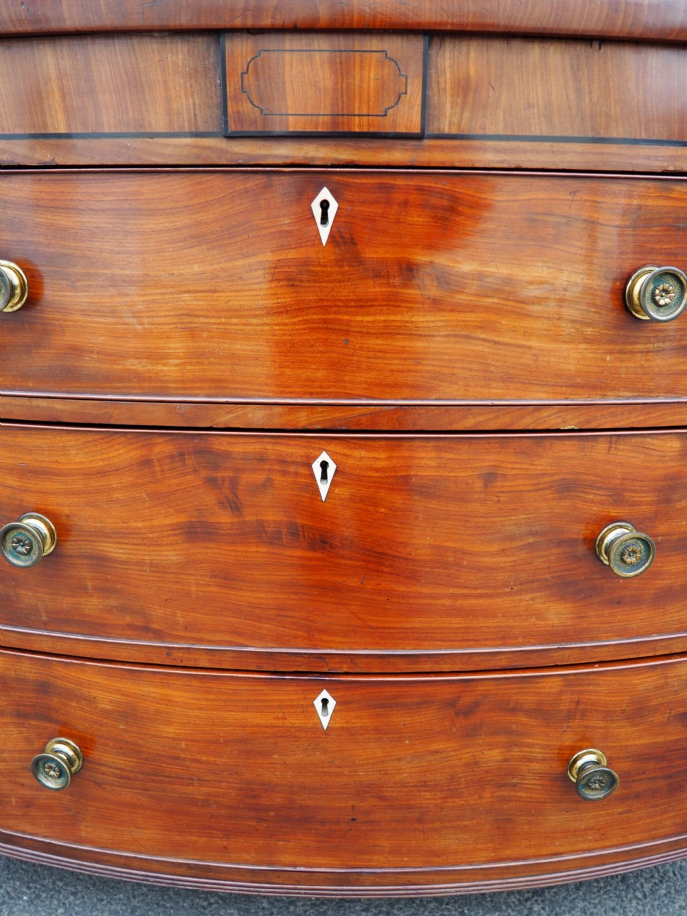 A Regency period mahogany bowfront chest of drawers featuring three full-width drawers, spiral-turned side columns, and circular brass handles. View VIII
