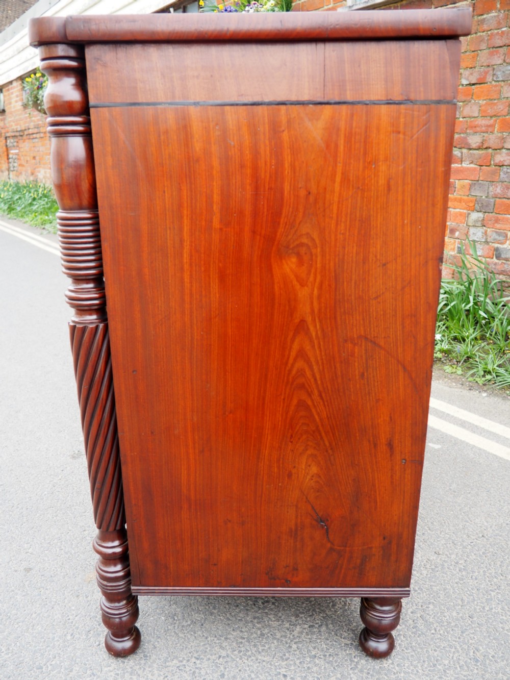 A Regency period mahogany bowfront chest of drawers featuring three full-width drawers, spiral-turned side columns, and circular brass handles. View XII